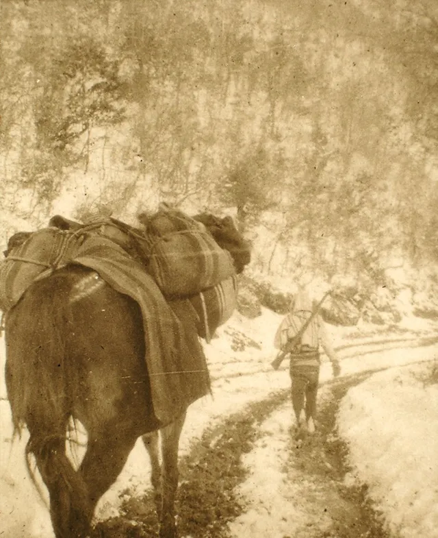 A 1903 photograph of a packhorse and a rifleman crossing a snowy mountain pass between Prizren and Gjakova.