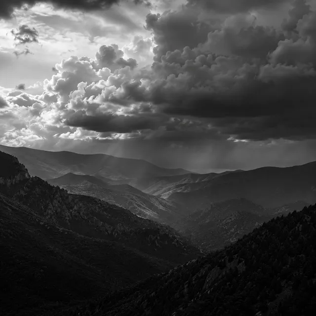 Shafts of light falling through cloud over the ridged valleys of the Accursed Mountains.
