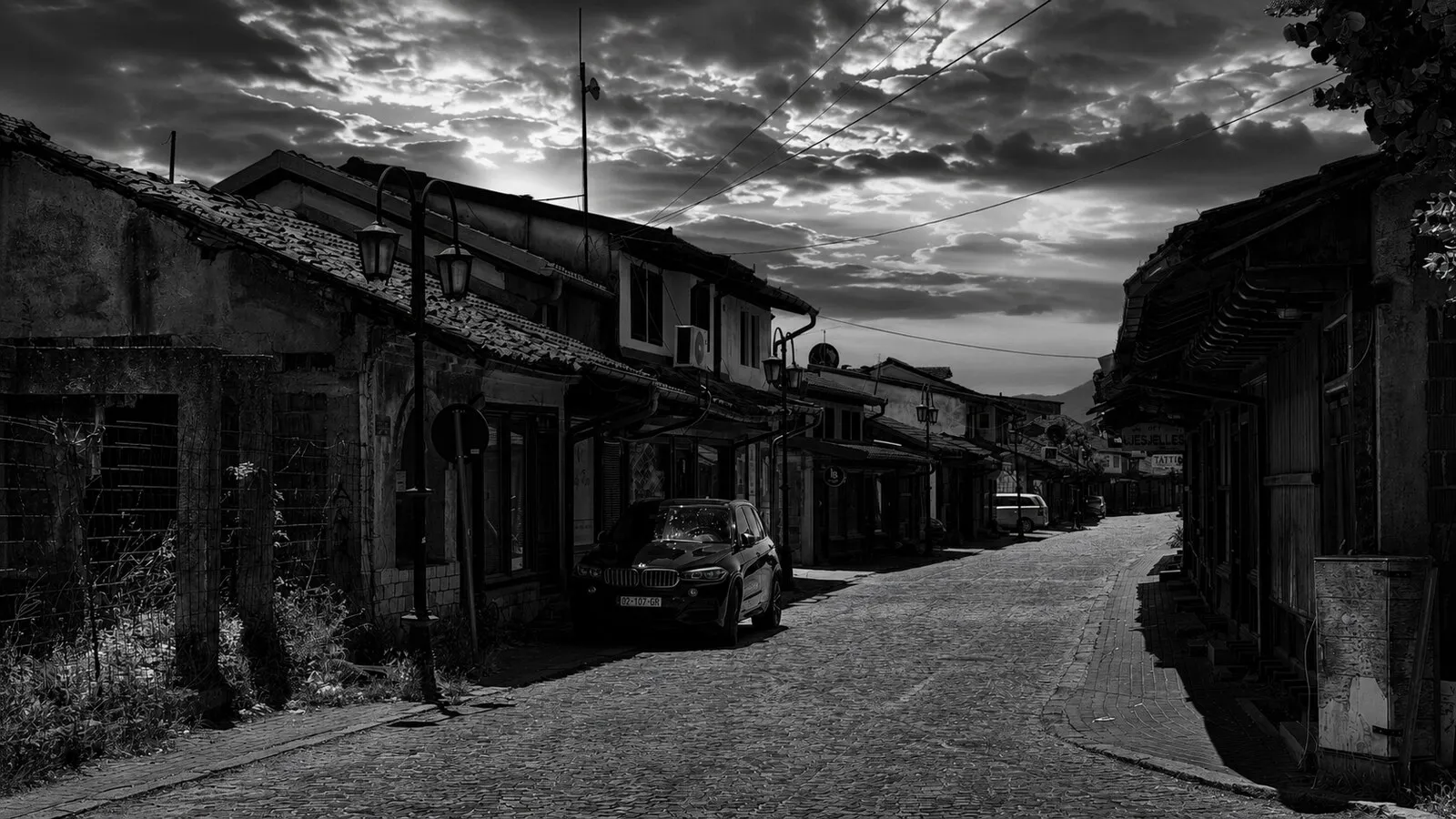 A rebuilt cobbled lane of timber-fronted shops in Gjakova's old bazaar at dusk.