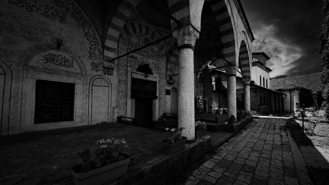 A wide view of the mosque's painted porch and courtyard under a dark sky.