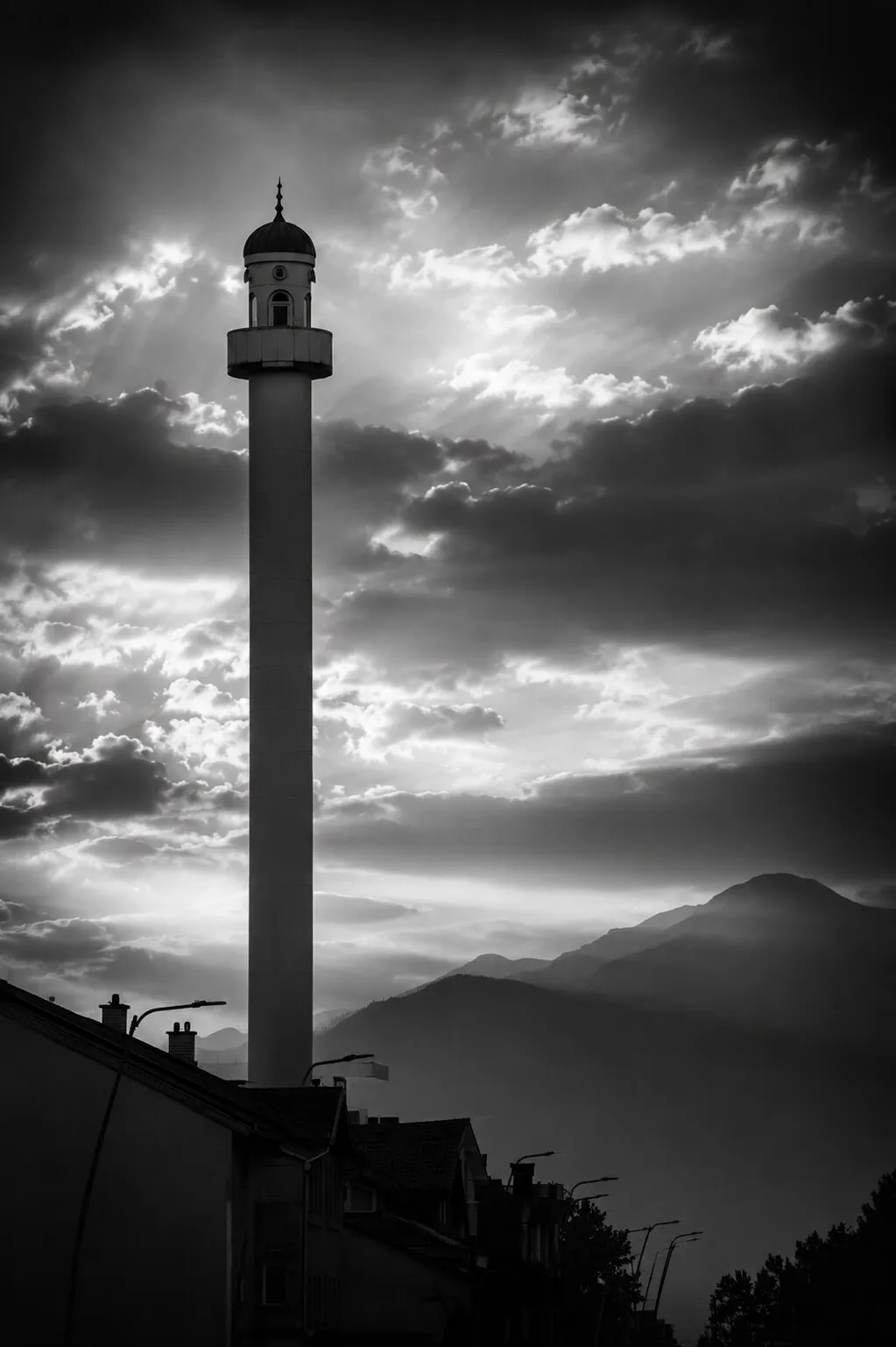 A slender mosque minaret rising against a dramatic evening sky.
