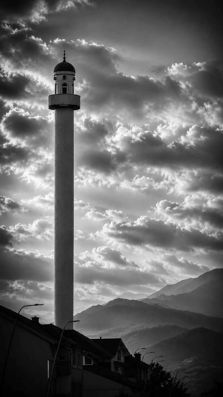 The slender minaret of the Xhamia e Qylit against a dramatic sky, mountains beyond.