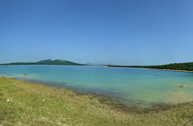 A panorama of Radoniq Lake among low hills.